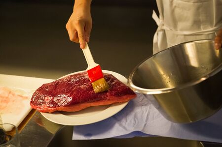 Preparing a big piece of meat to be roasted. Buttering and marinating a meat surface