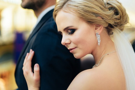 Beautiful wedding couple in Moscow, the bride and groom in a white dress in the interior, happy new familyの写真素材