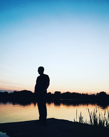 silhouette of a man on the background of the setting sun and the lake 1の写真素材