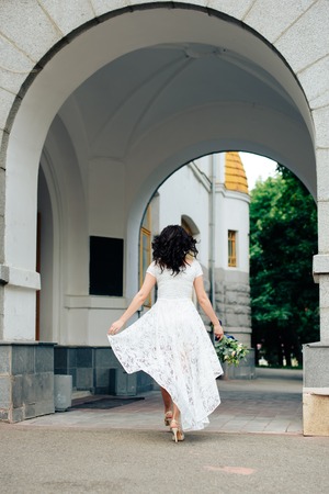 bride in a white dress with a bouquet of flowers on a building background with an 1の写真素材