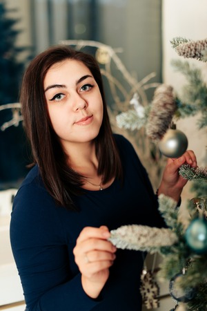 girl in a blue dress in a New Year decor near a decorated Christmas treeの写真素材