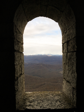 old stone window in the form of an arch with a view of the mountains 1の写真素材