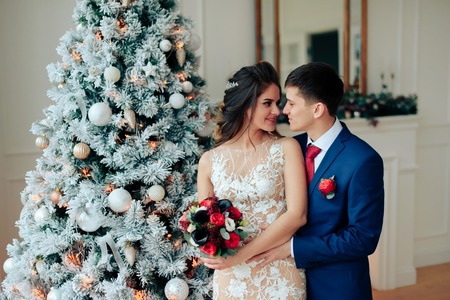 Beautiful young loving wedding couple in new year interiorの写真素材