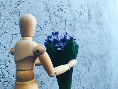 wooden faceless man gives blue flowers oneの写真素材