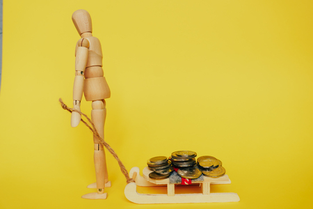 wooden man on a yellow background with coinsの写真素材