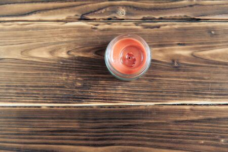 red candle in a glass jar on a wooden backgroundの写真素材