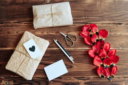gifts, scissors and red petals on a wooden background
