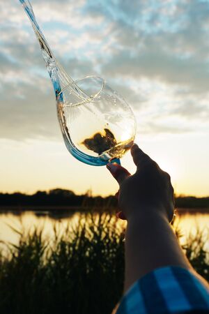 a glass of water on the background of the river and the sunsetの写真素材