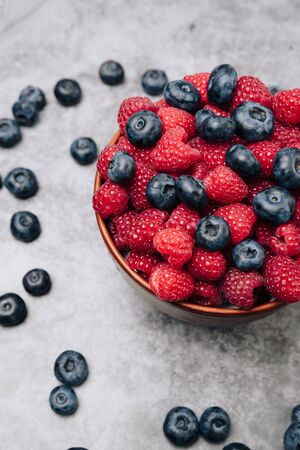 clay plate with tasty bright raspberries on a gray backgroundの写真素材