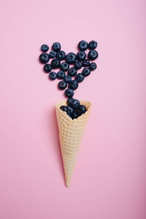 blueberries on a pink background with a waffle cone for ice creamの写真素材