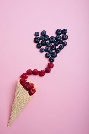 blueberries on a pink background with a waffle cone for ice cream