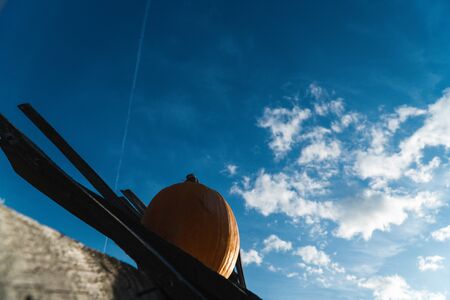 yellow pumpkin on a background of blue sky on a wooden surfaceの写真素材