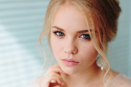 portrait of a beautiful girl with blue eyes and white hair with a bouquet of flowers and a white...