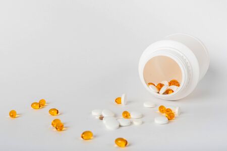 scattered pills of different shapes and colors on a white background