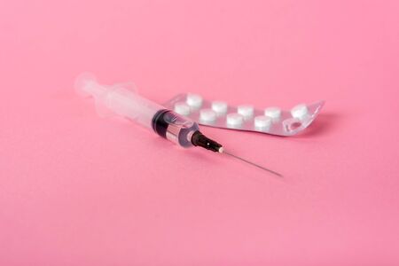 scattered pills of different shapes and colors on a pink background