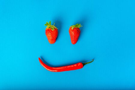 red ripe strawberries and chili peppers on a blue backgroundの写真素材