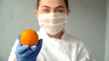 woman doctor offering an orange to boost immunity 1の写真素材