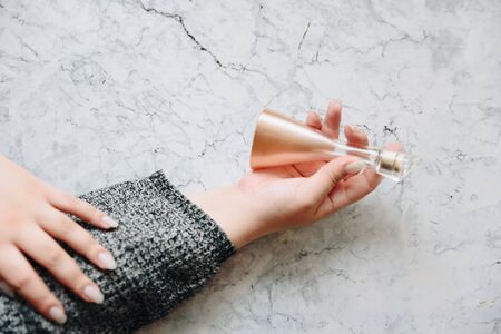 the hand of a young woman in grey holds perfumeの写真素材