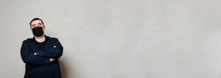 man in black shirt and black hospital mask on gray wall backgroundの写真素材