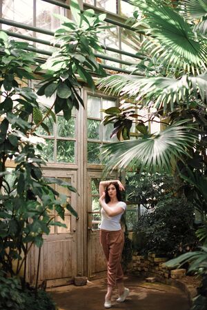 A beautiful young girl walks through an old greenhouse. Woman in the Botanical gardenの写真素材