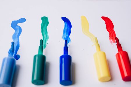 multi- colored nail polishes and traces of them on a white background