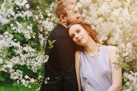 young beautiful couple in the garden against the background of cherry blossomsの写真素材