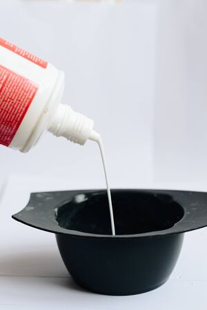 stylist kneads hair dye in a black container close upの写真素材