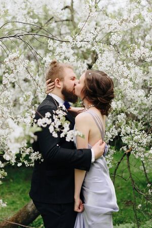 young beautiful couple in the garden against the background of cherry blossomsの写真素材