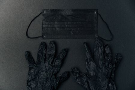 Black medical mask and black gloves on a black background 1