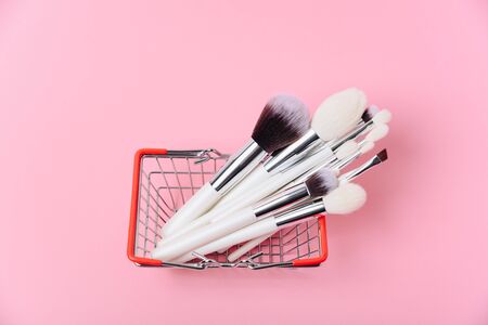 Makeup brushes on a pink background in the basket close upの写真素材