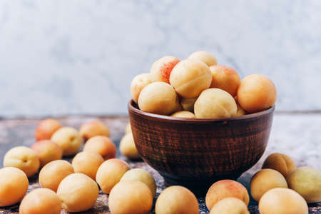 Lots of ripe yellow apricots close up in a crockery on the tableの写真素材