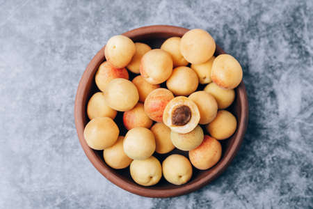 Lots of ripe yellow apricots close up in a crockery on the tableの写真素材