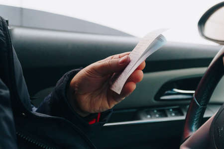a man in a car holding a receipt