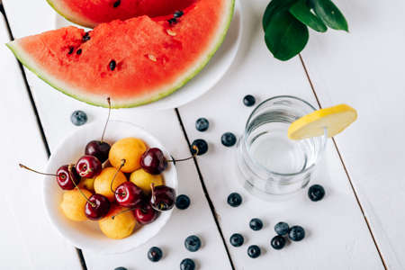 Summer still life of fresh fruit and berries on a white wooden surface