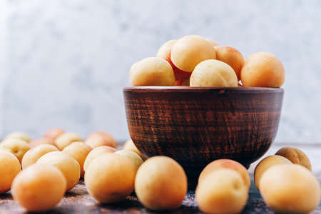 Lots of ripe yellow apricots close up in a crockery on the tableの写真素材
