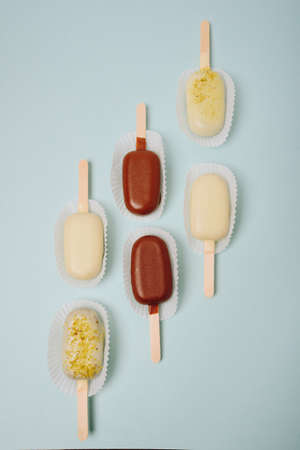 Chocolate cake in the form of ice cream on a stick on a white plate and a colored background