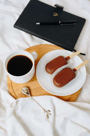 Chocolate cake in the form of ice cream on a stick on a white plate and a colored background