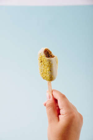 Chocolate cake in the form of ice cream on a stick on a white plate and a colored backgroundの写真素材