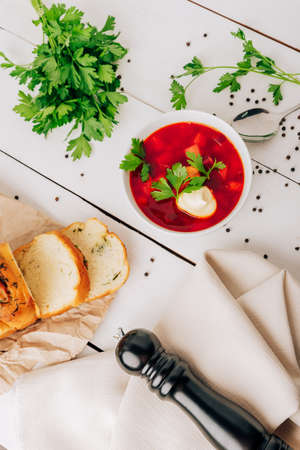 Borscht with fresh bread on a natural wooden background. Red beetroot soup with fresh bread