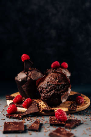 chocolate cupcakes close up on a dark background with chocolate and raspberries