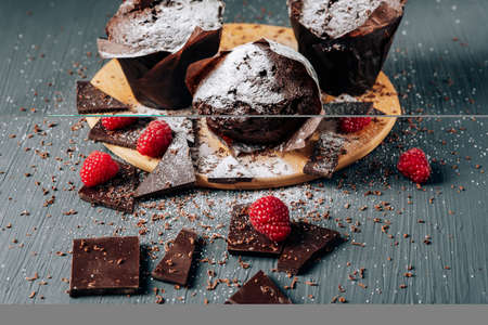 chocolate cupcakes close up on a dark background with chocolate and raspberries