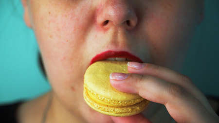 Girl eating macaroon cake close upの写真素材