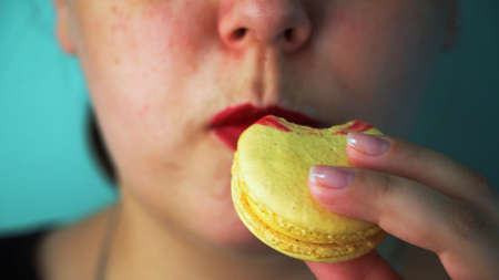 Girl eating macaroon cake close upの写真素材