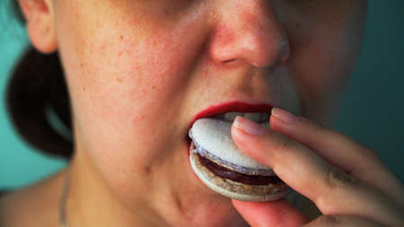 Girl eating macaroon cake close up