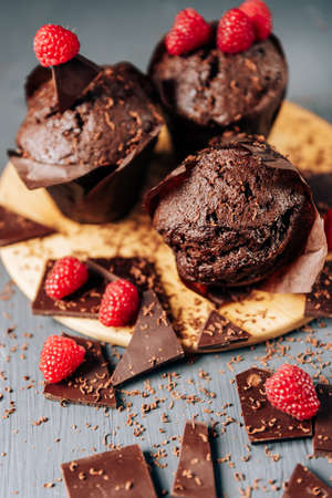 chocolate cupcakes with raspberries and bitter chocolate close-up on a light backgroundの写真素材