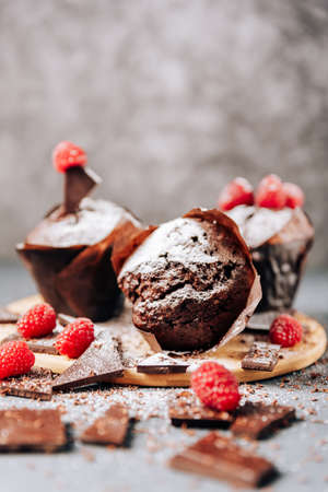 chocolate cupcakes with raspberries and bitter chocolate close-up on a light backgroundの写真素材