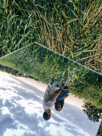 A young couple a woman with a man in a wheat field at sunset in the reflection of a mirrorの写真素材