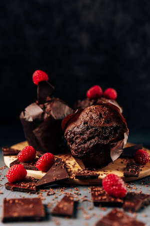 chocolate cupcakes close up on a dark background with chocolate and raspberries