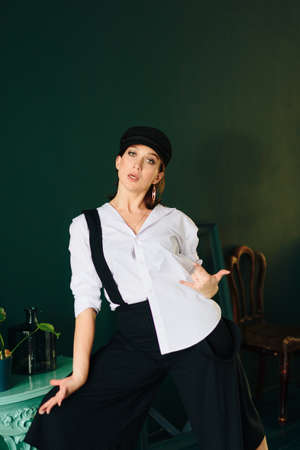 Portrait of a beautiful young woman in a white shirt and black pants in the Studio