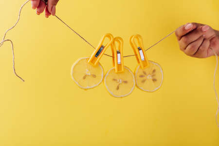 Lemon slices on a clothespin on a rope on a yellow background